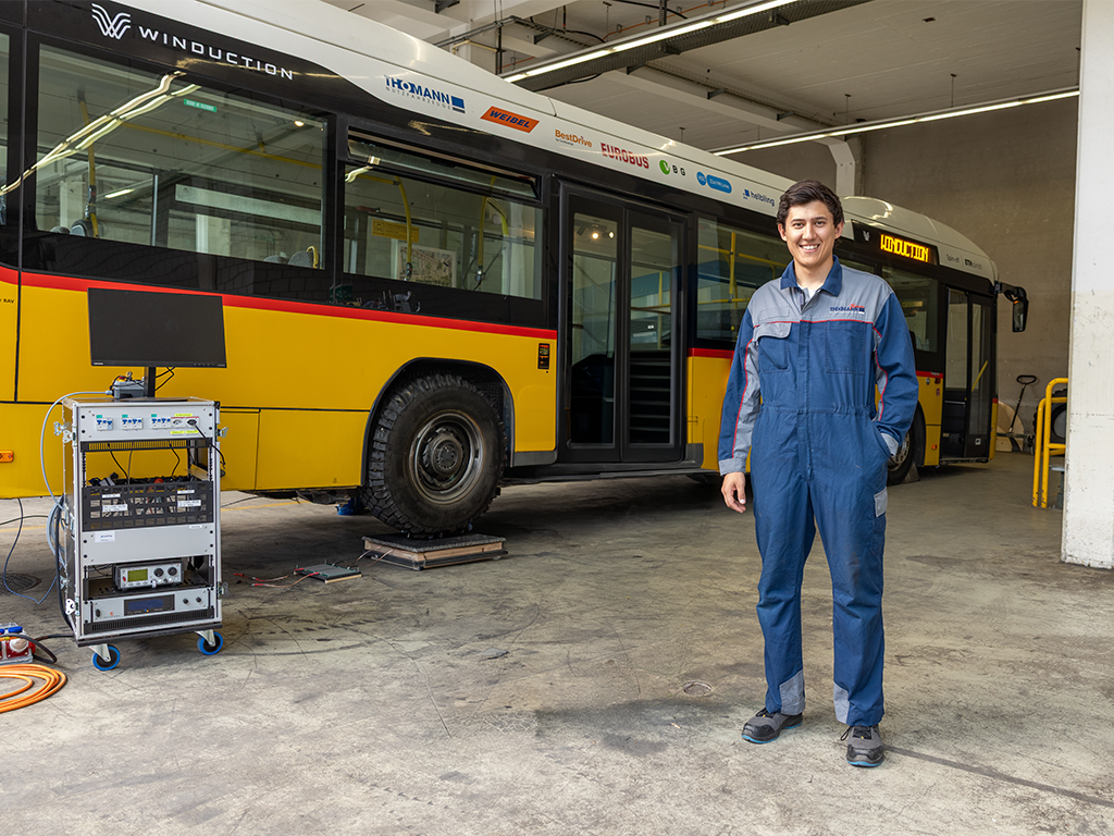 Sonam Bhuka steht in Arbeitskleidung vor einem Bus in einer Halle in Winterthur.